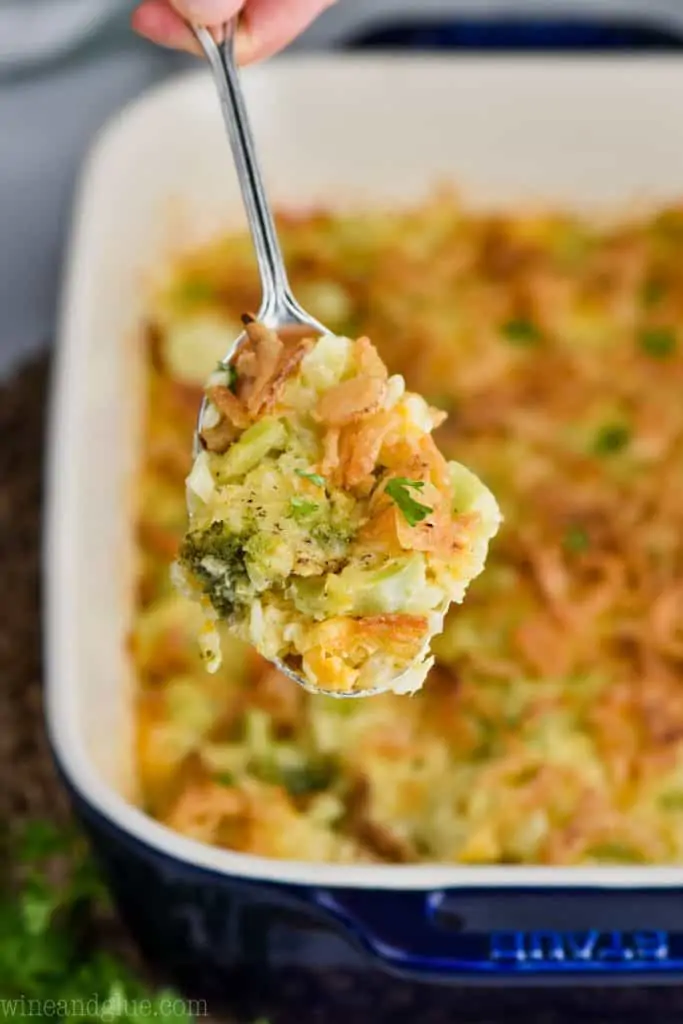 spoonful of broccoli and rice casserole coming out of a casserole dish