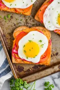 hummus toast layered with pickled red onions, tomatoes, and a fried egg