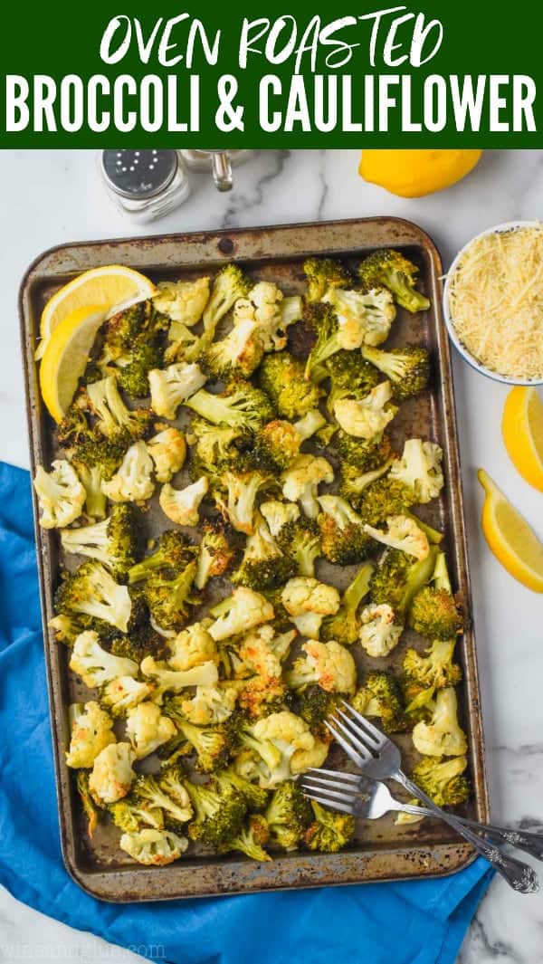 overhead view of roasted broccoli and cauliflower on a baking sheet garnished with lemon