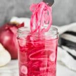 quick pickled red onions being pulled from a canning jar - 17