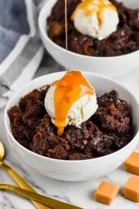 dripping caramel sauce over ice cream on a bowl of salted caramel crock pot brownies