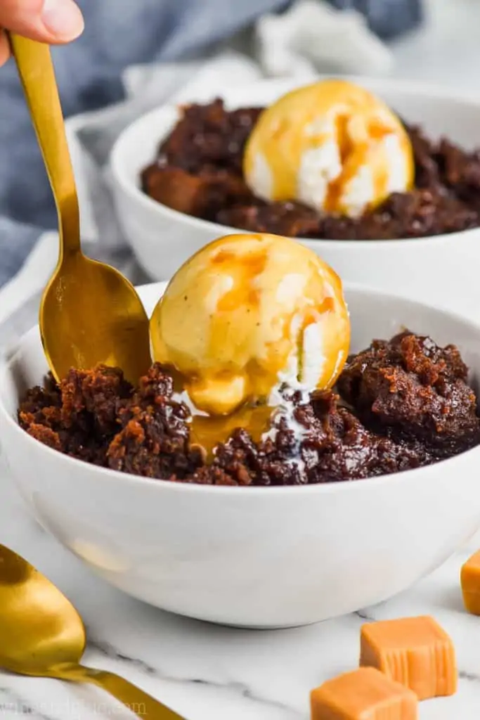 spoon digging into a white bowl of slow cooker brownies