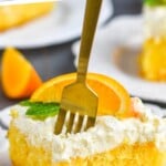 pinterest graphic of piece of orange pig pickin' cake on a white plate with orange slice and two mint leaves on top and fork digging into cake, says: "the best pig pickin' cake simplejoy.com"