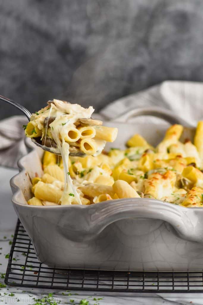 cheesy chicken noodle casserole being pulled out of casserole dish
