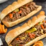 two italian beef sandwiches with curly fries around them on a granite surface - 17