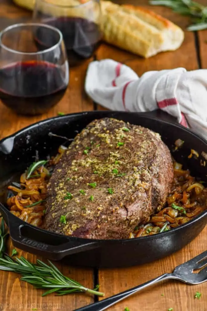 front view of whole roast beef recipe on a bed of caramelized onions