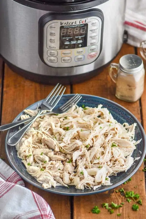 shredded instant pot chicken on a plate in front of an instant pot