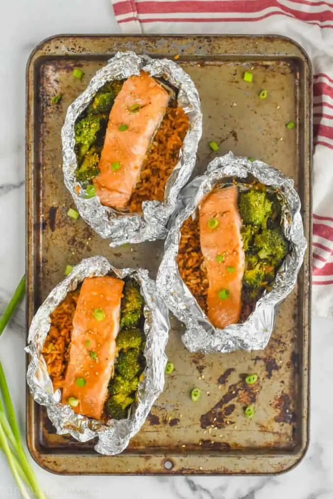 three baked teriyaki salmon foil packets on a baking sheet