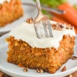 a fork sticking into a piece of carrot cake that is topped with cream cheese frosting - 17