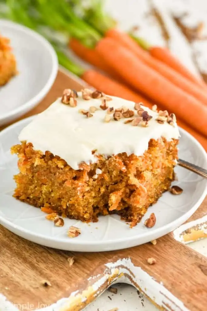 a piece of homemade carrot cake on a small plate with a bite missing