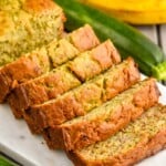 sliced loaf of Banana Zucchini Bread. Bananas and zucchini beside cutting board. - 13