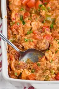 spoon digging into a casserole dish of cajun chicken and rice