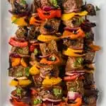 steak kabobs, skewered with metal skewers and flavored with fajita seasoning, on a white plate