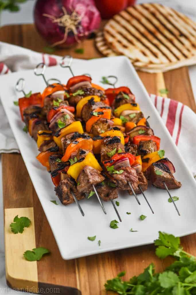 side view of steak kabobs on a white plate