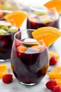 glass of red sangria recipe with an orange wedge for garnish