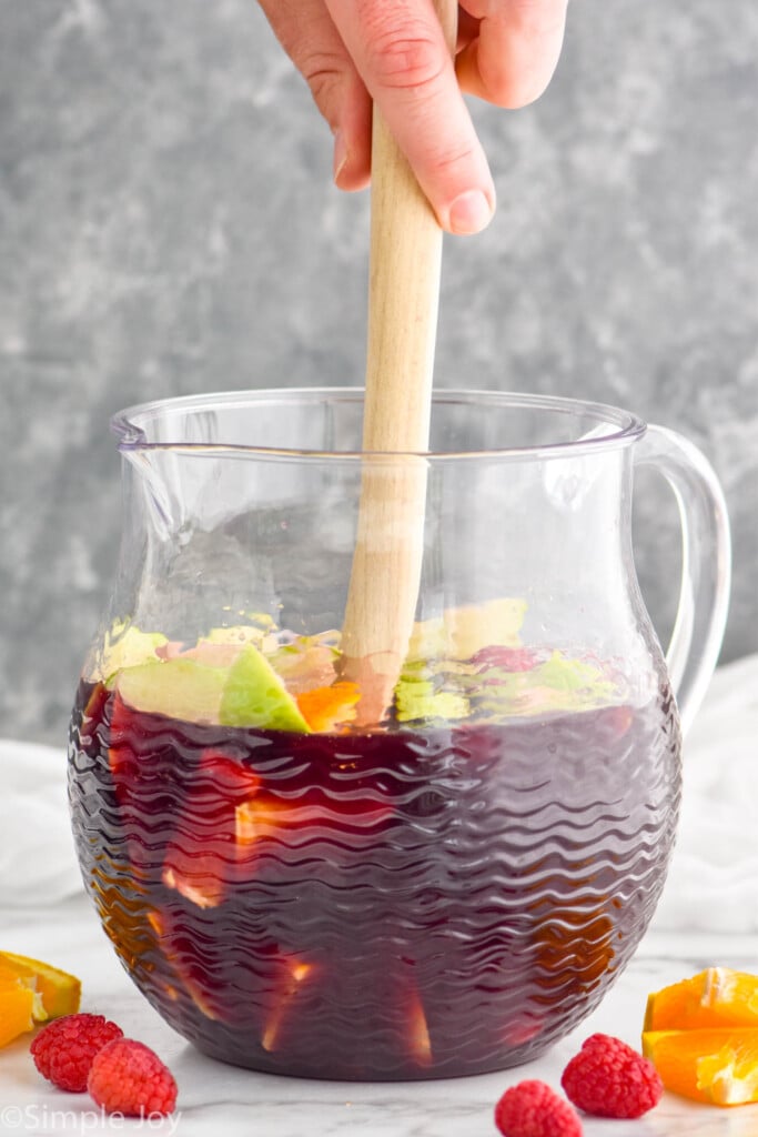 large wooden spoon stirring a pitcher of red wine sangria recipe