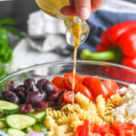 pinterest graphic of pouring dressing over greek pasta salad that says: the best greek pasta salad simplejoy.com