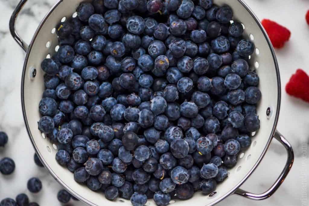 A white strainer filled with blueberries 