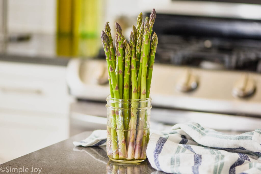 small mason jar with water and asparagus on a kitchen counter