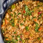 overhead view of peanut butter stir fry noodles in a large skillet, topped with fresh cilantro and chopped peanuts