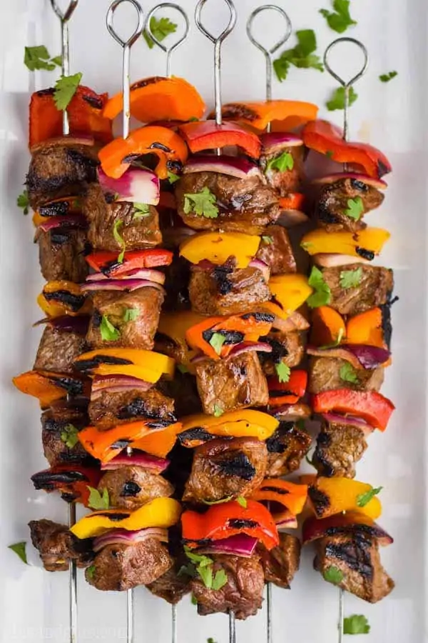 steak kabobs, skewered with metal skewers and flavored with fajita seasoning, on a white plate