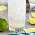 pinterest graphic of close up view of a gin rickey cocktail in a tall glass garnished with a lime wedge, says: "gin rickey simplejoy.com"