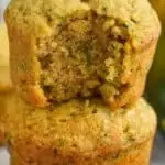 a zucchini muffin with a bite missing on top of a whole muffin
