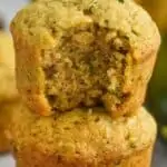 a zucchini muffin with a bite missing on top of a whole muffin