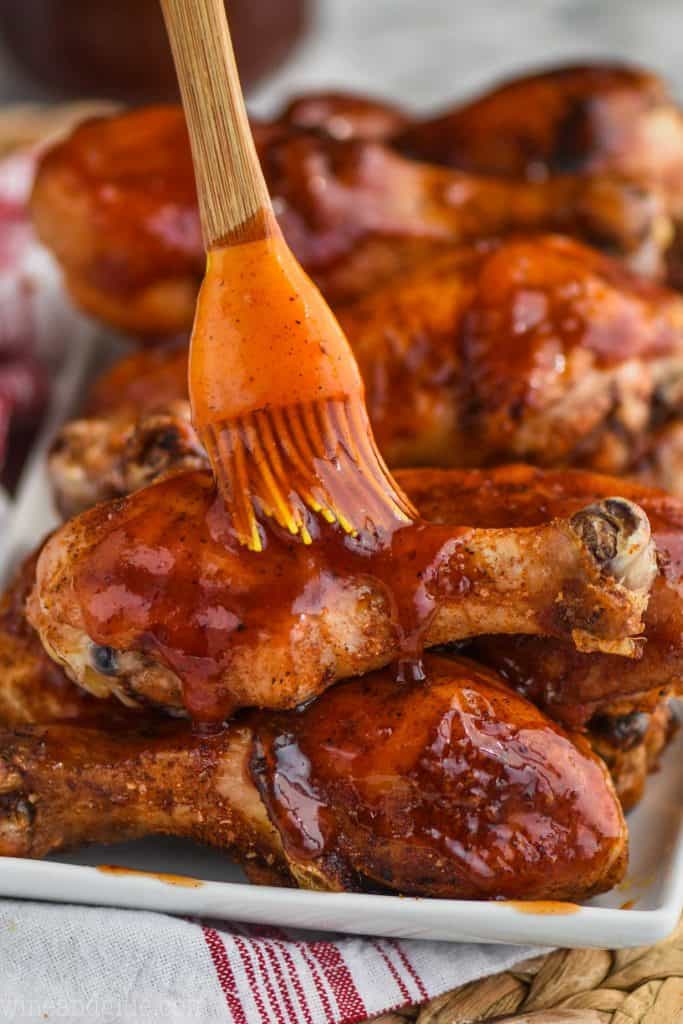 brushing bbq sauce on grilled chicken legs