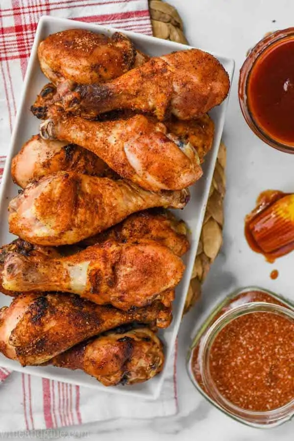 overhead view of chicken drumsticks on a white rectangular plate made with chicken spice rub