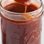 mason jar full of bbq sauce with spoon dishing some out