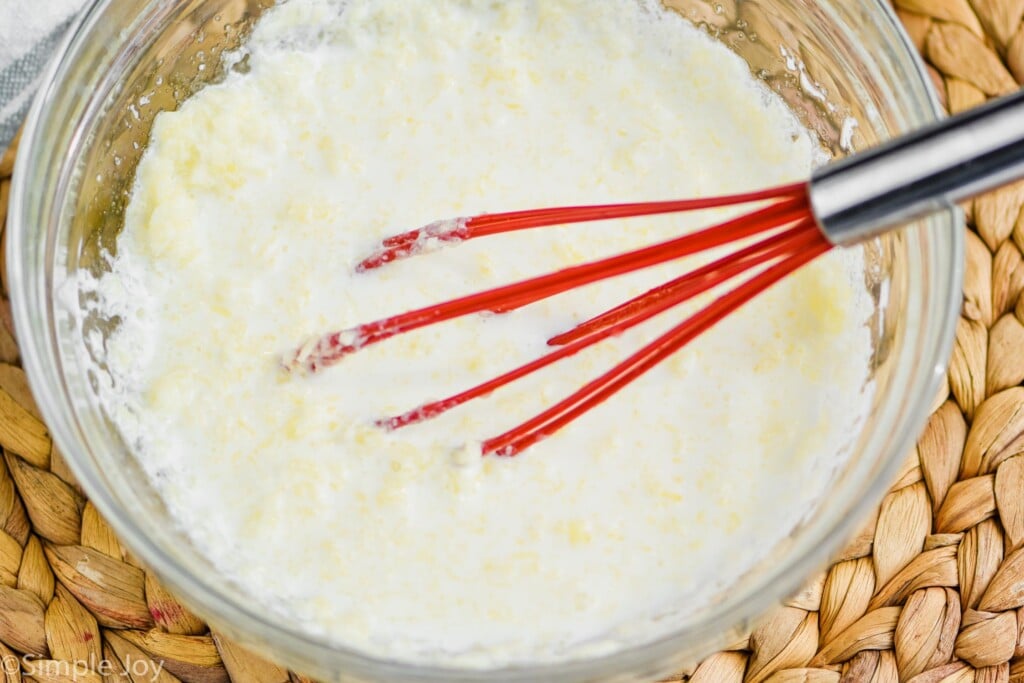 bowl of melted butter and butter milk with red whisk for drop biscuit recipe