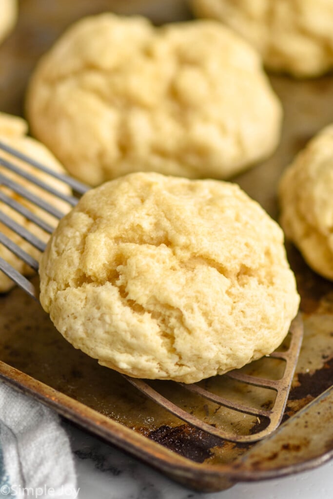 fast and easy drop biscuits being picked up by a metal spatula off a baking sheet