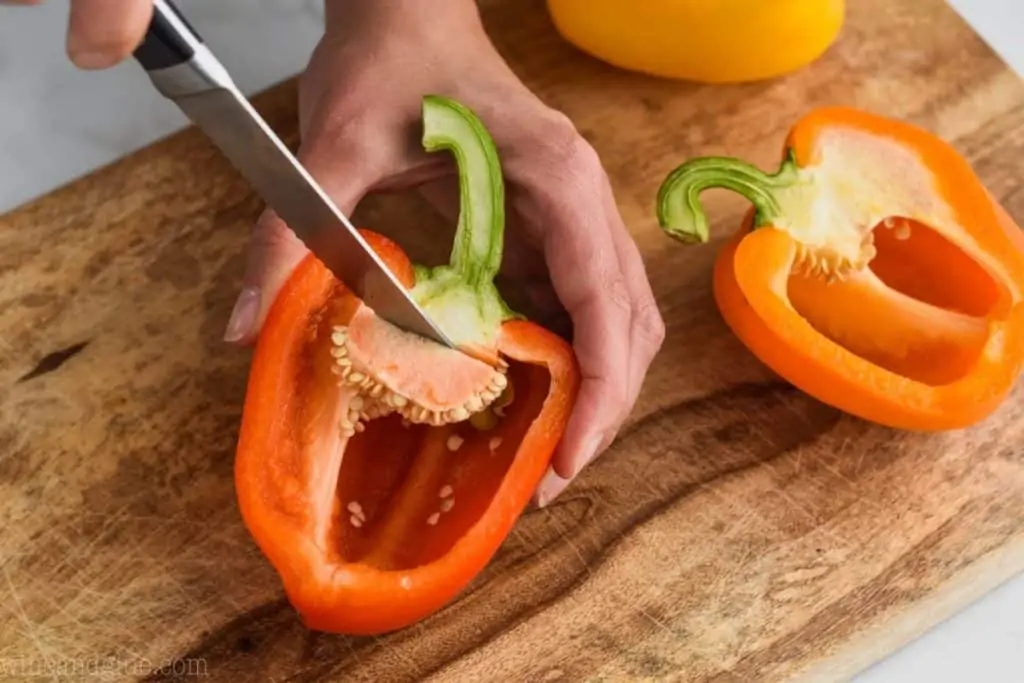woman cutting the seeds out of the inside of a stuffed pepper