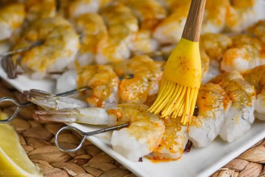 brushing cajun marinade on shrimp skewers