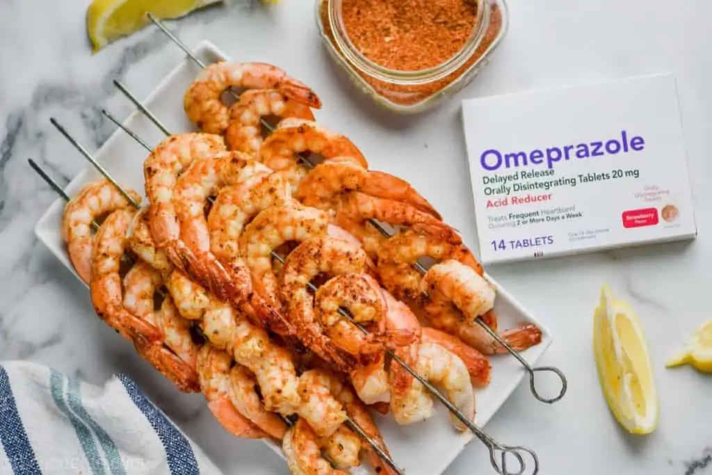 A plate full of Cajun Shrimp Skewer with lemon slices around the plate and a box of Omerprazole 