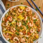 overhead view of bowl of shrimp fried rice recipe on a wood cutting board