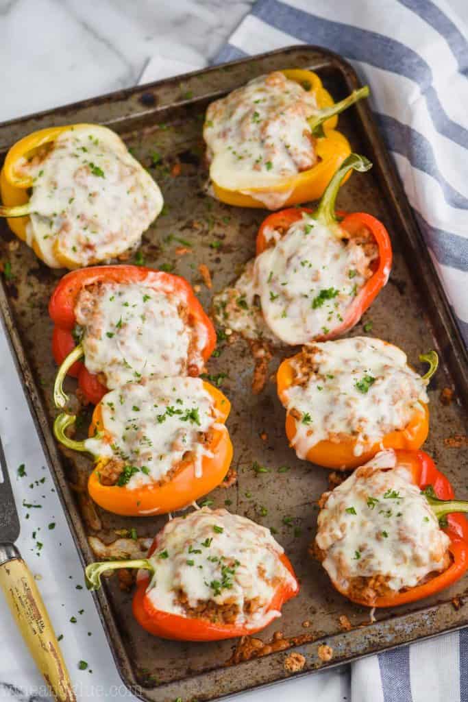 eight ground turkey stuffed bell peppers (orange, yellow, and red), cooked and covered in melted cheese on a baking sheet