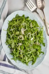 overhead view of an oval plate with an arugula salad on it