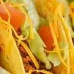 close up view of a taco made with homemade taco meat recipe and topped with chopped lettuce, tomatoes, and shredded cheese