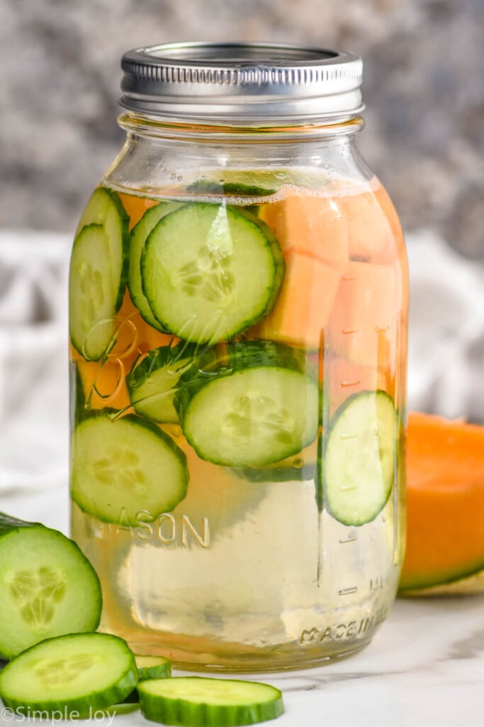 a mason jar full of cucumber slices and watermelon chunks to make infused water