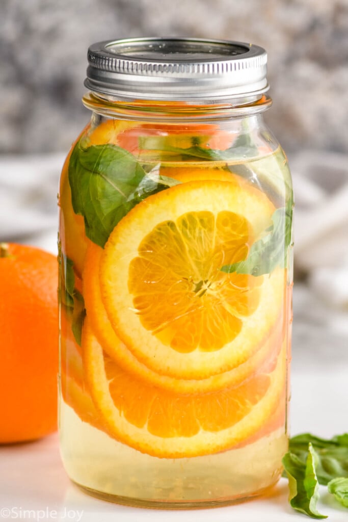a mason jar filled with basil and orange slices to make infused water