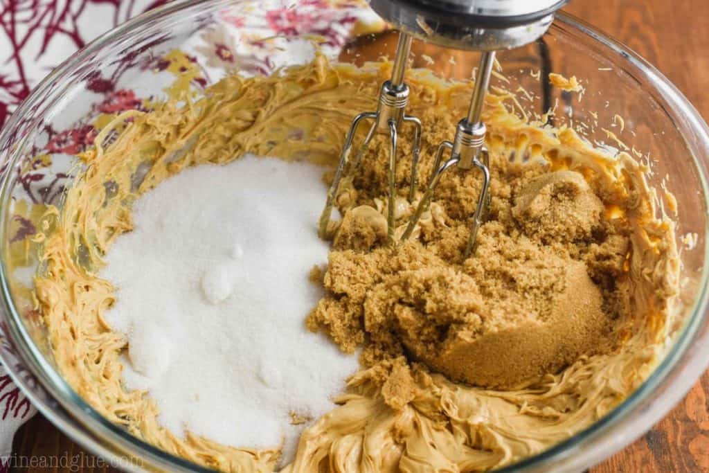 white and brown sugar being added to the batter of pumpkin peanut butter cookies with the beaters of a hand mixer being put into the bowl - 12