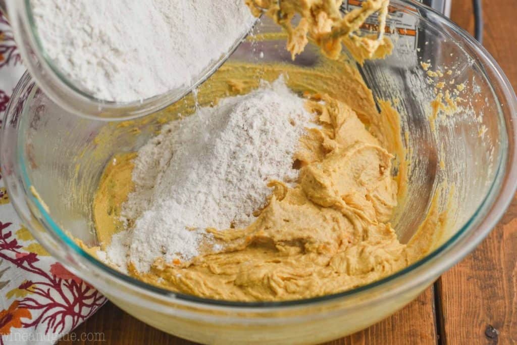flour being poured into a bowl of pumpkin peanut butter cookie batter - 14