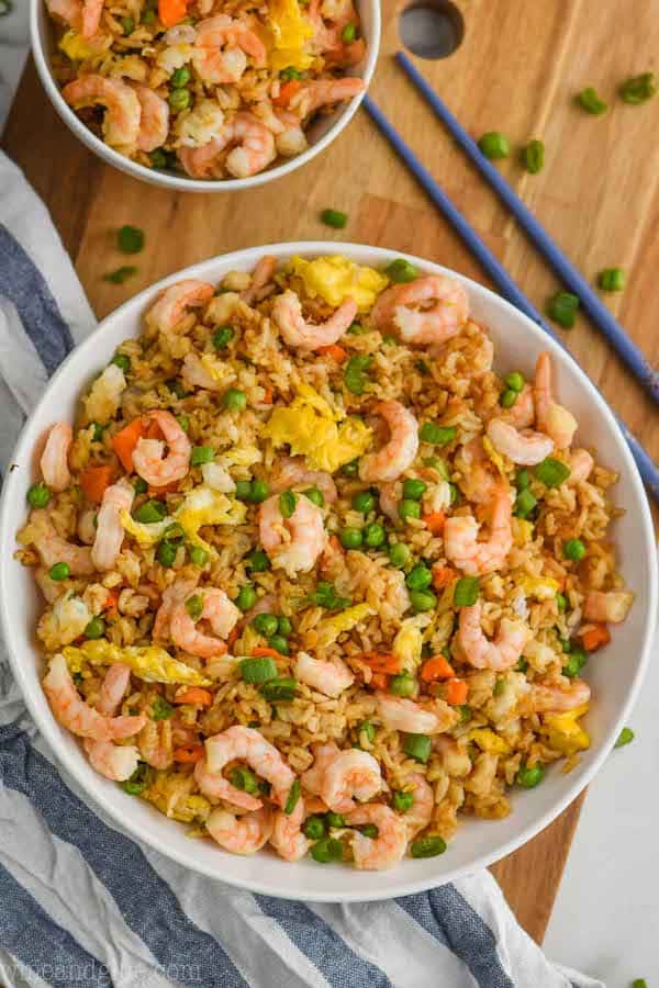 overhead view of bowl of shrimp fried rice recipe on a wood cutting board