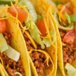 close up view of a taco made with homemade taco meat recipe and topped with chopped lettuce, tomatoes, and shredded cheese