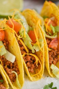 close up view of a taco made with homemade taco meat recipe and topped with chopped lettuce, tomatoes, and shredded cheese