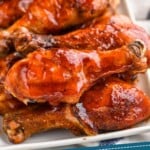 pinterest graphic of plate full of grilled chicken legs sitting on a striped napkin, says " the best grilled chicken legs, simplejoy.com"