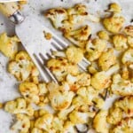 pinterest graphic of overhead view of roasted cauliflower on a parchment lined baking sheet, being dished up by a slotted spatula, says: "roasted cauliflower recipe, simplejoy.com"