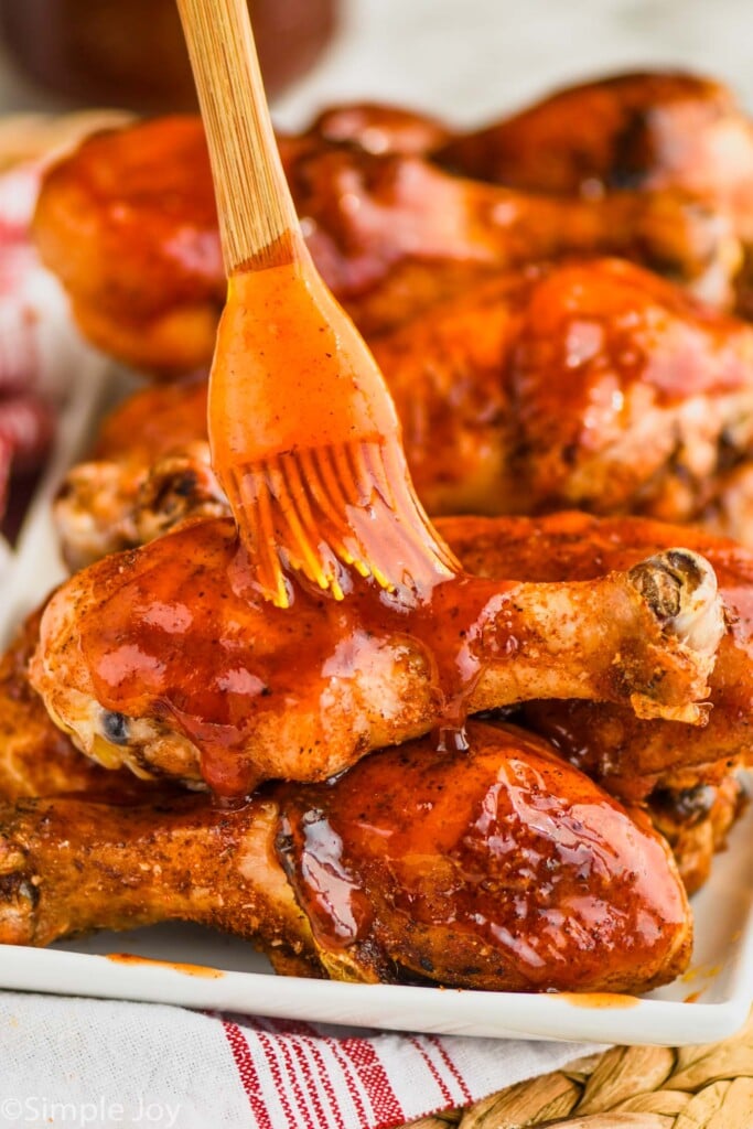 brushing bbq sauce on grilled chicken legs